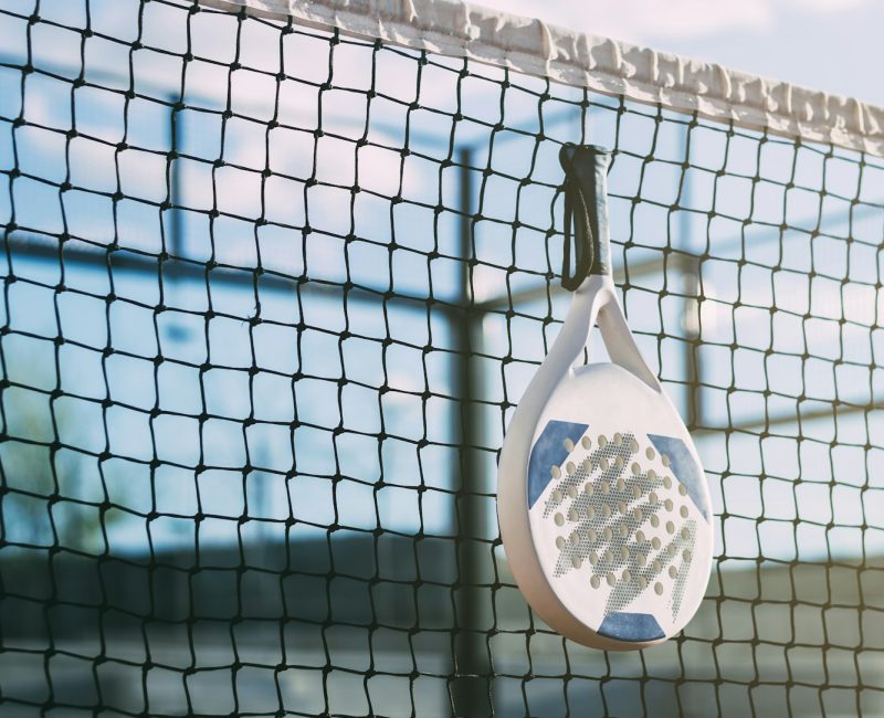 Padel blade racket hanging on the net